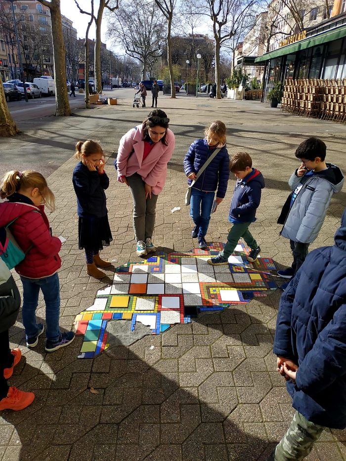 Alice Laurent et un groupe d'enfants observent une oeuvre de mosaique sur le trottoir