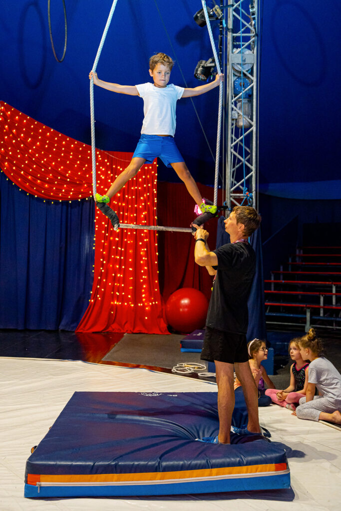 petit garçon debout sur un trapèze sous le chapiteau du cirque Imagine