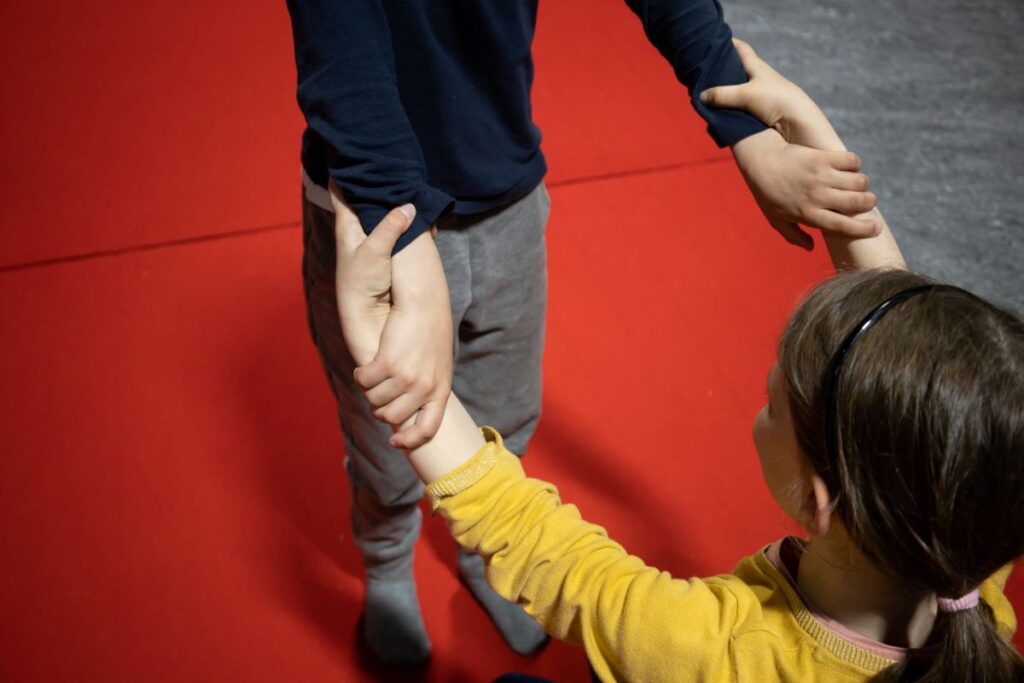 deux enfants se tiennent les poignets avant de se lancer dans un porté, en cours de cirque