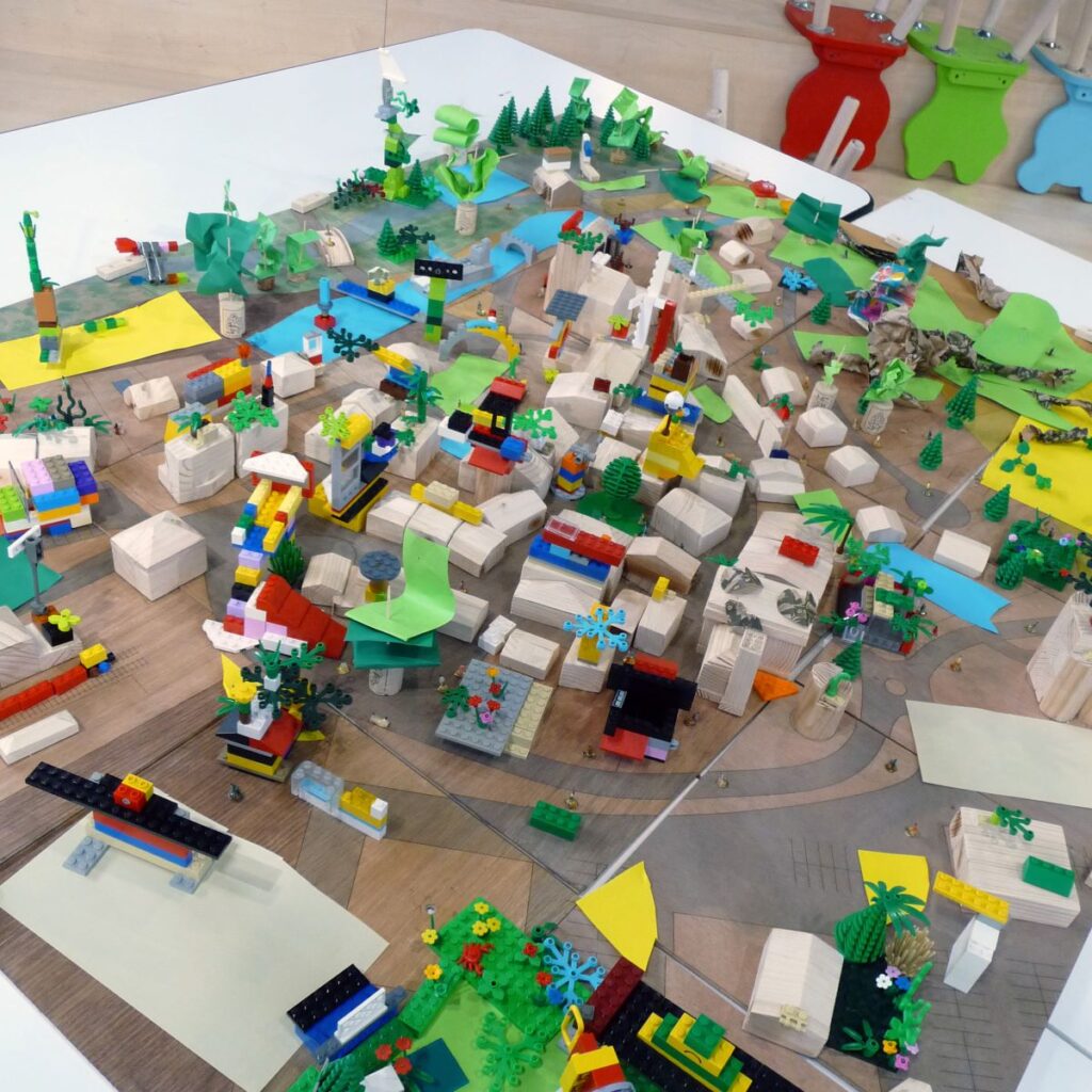 maquette de Lego, de pièces en bois et de morceaux de papier vue de dessus