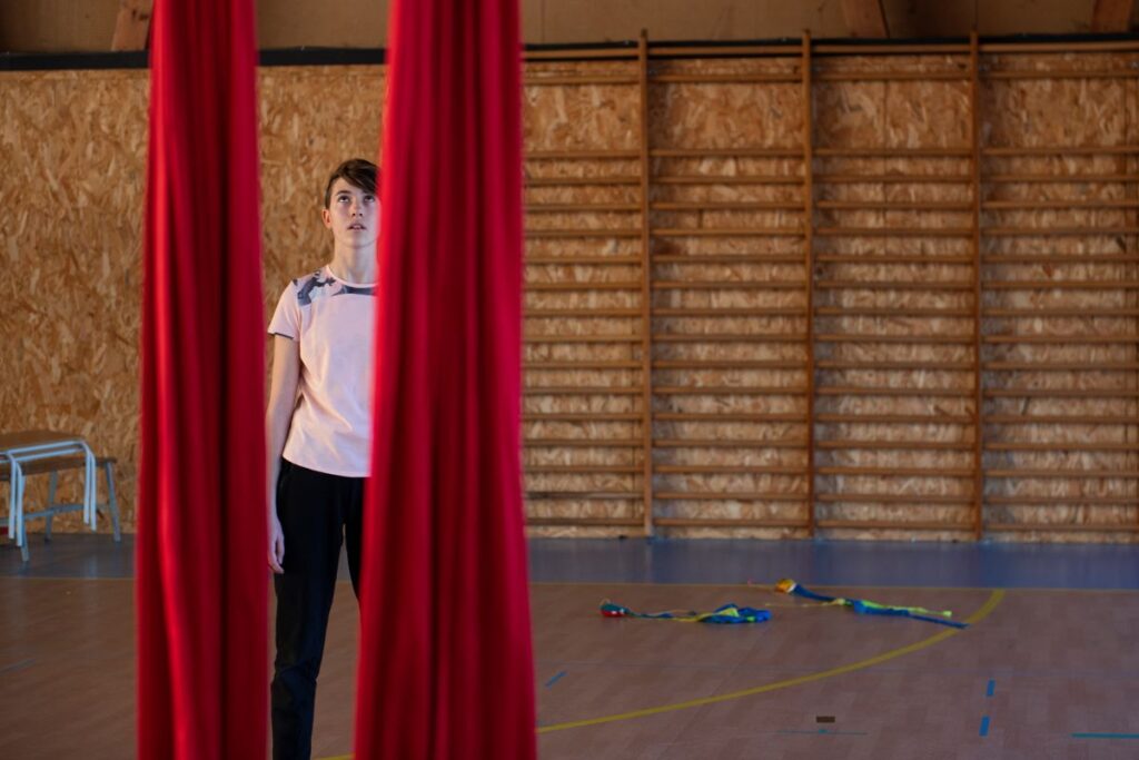 Jeune fille devant les pans de tissu rouge dans le gymnase du collège Les Battières