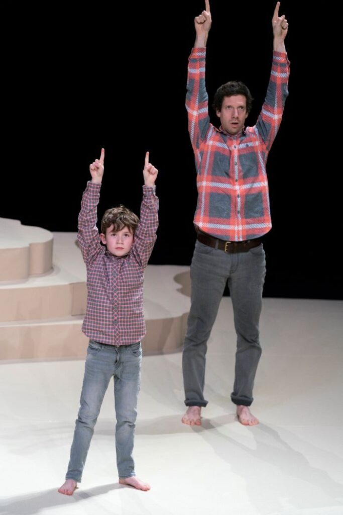 un homme et un enfant lèvent les bras en l'air sur une scène de théâtre