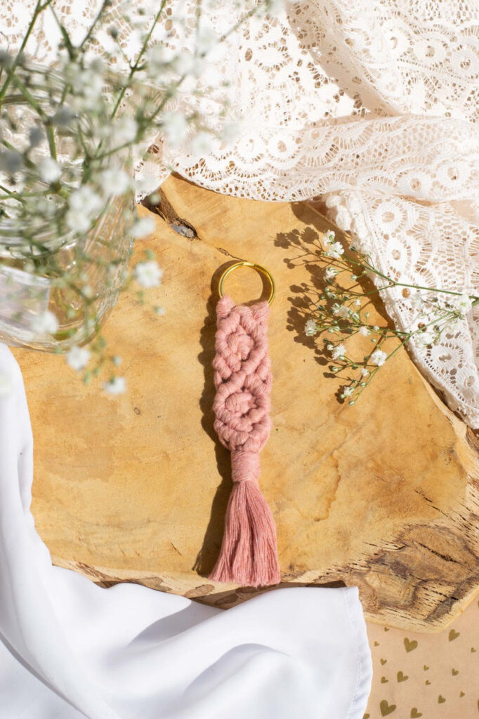 porte clefs en macramé rose entouré de fleurs et de dentelles