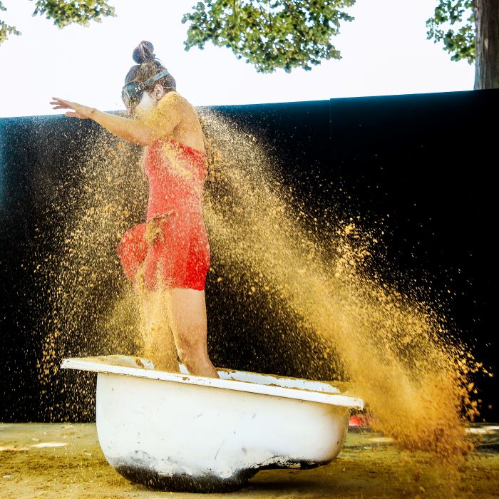 une jeune femme debout dans une baignoire dans une nuée de paillettes dorées