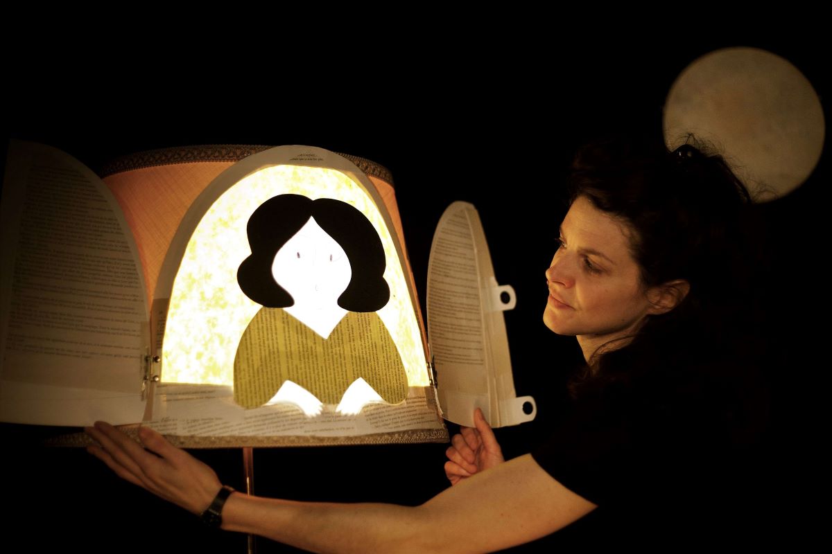 Une jeune femme a coté d'une lampe illustrée d'un visage de femme