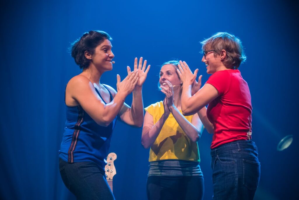 trois femmes en train de chanter sur un fond bleu