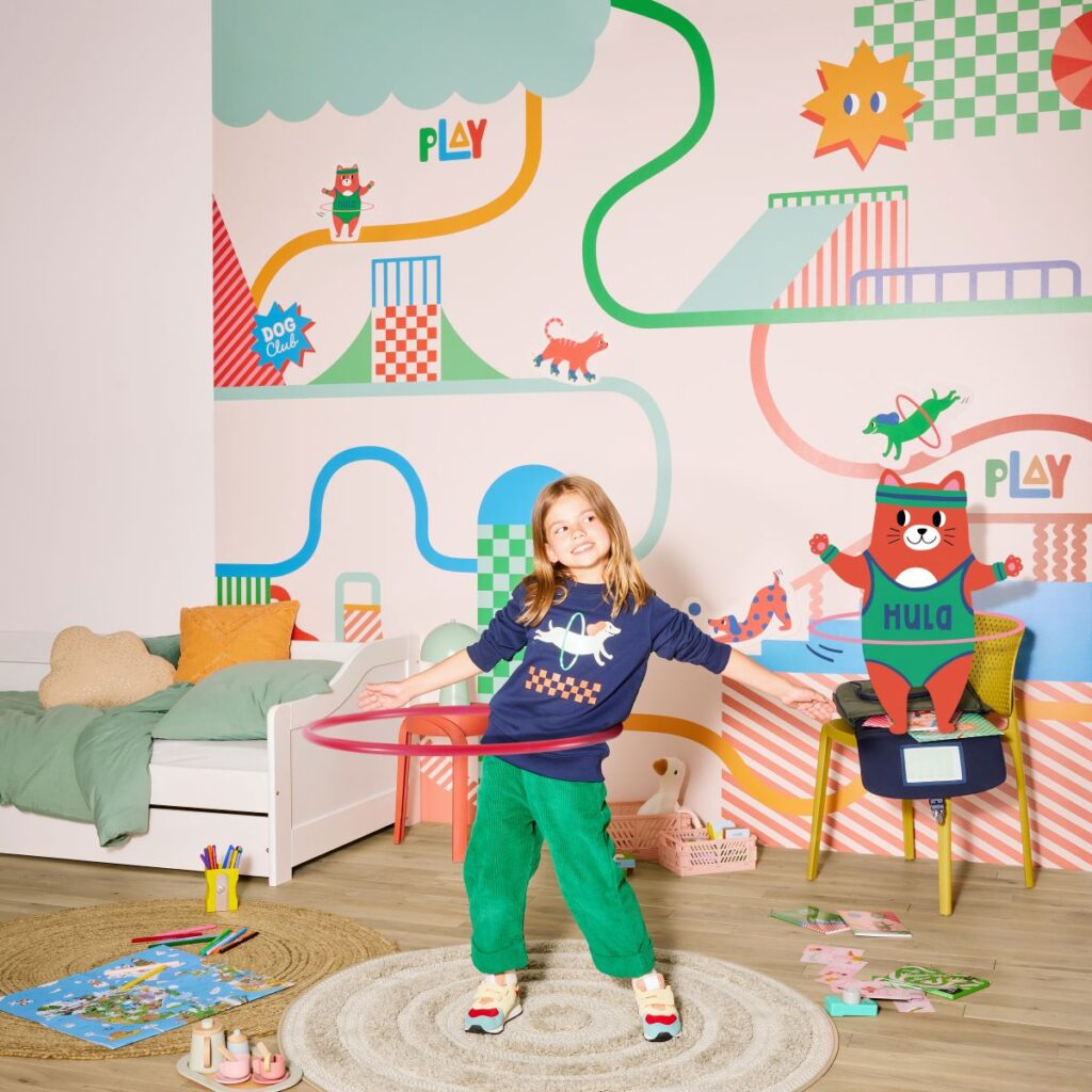 Petite fille faisant du cerceau dans une chambre d'enfant avec papier peint Cha Cha Pop pour 4Murs