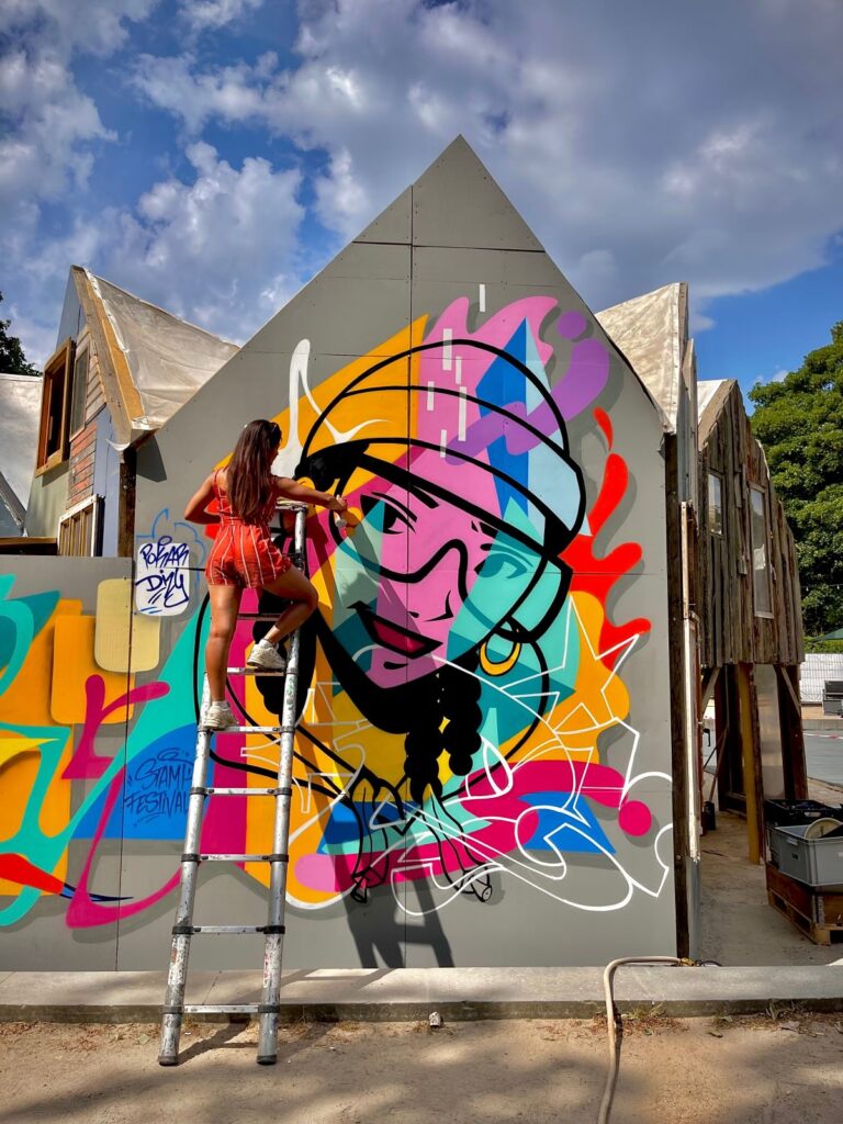 La street artist Dizy de dos devant l'une de ses oeuvres dans la rue